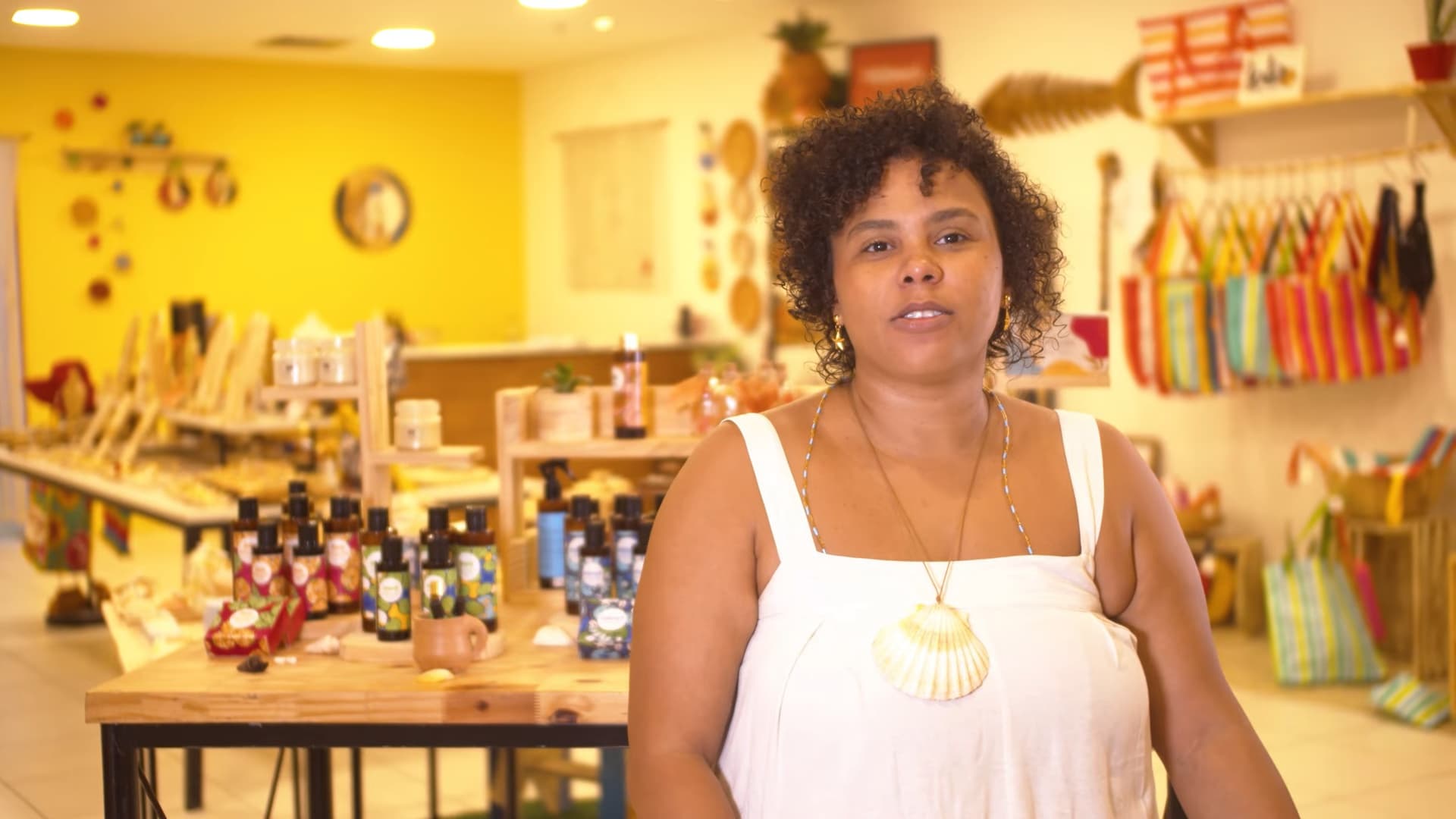 Empreendedora da Abebé Cosméticos na própria loja, com a linha de produtos sobre a mesa